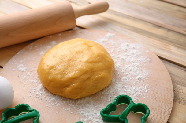 Pasta cruda per biscotti con stampi e mattarello sul tavolo di legno
 - Foto, immagini