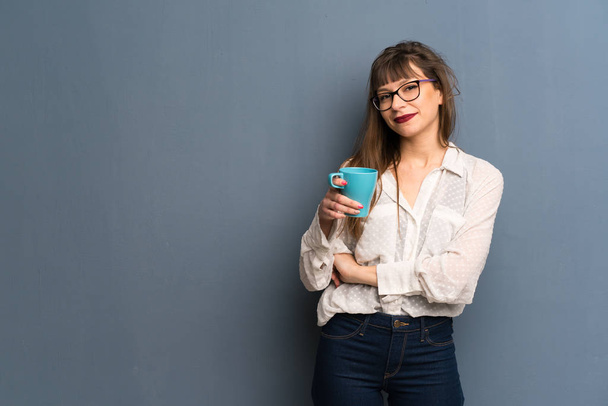 Femme avec des lunettes sur le mur bleu tenant une tasse de café chaud
 - Photo, image
