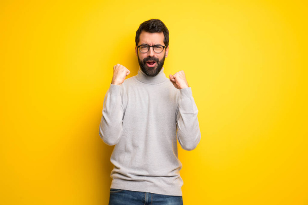 Man with beard and turtleneck celebrating a victory in winner position - Foto, immagini