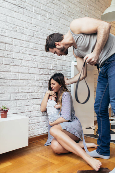Violencia familiar - hombre nervioso discutiendo con su esposa mientras ella sostiene a su bebé
.  - Foto, imagen