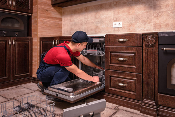 Fiatal férfi technikus konyhában mosogatógép javítás - Fotó, kép