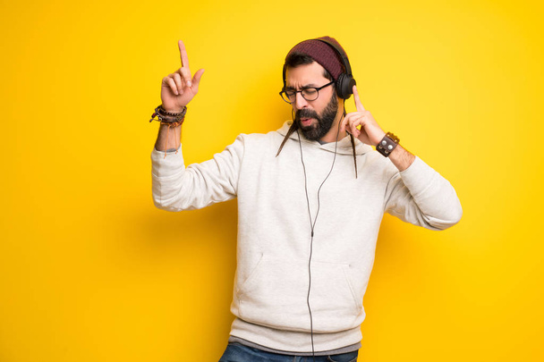 Hippie-Mann mit Dreadlocks hört Musik mit Kopfhörern und tanzt - Foto, Bild