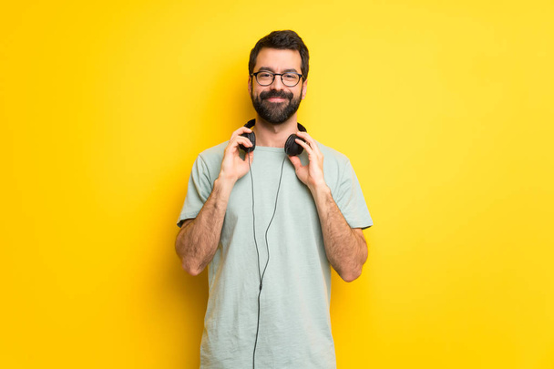 Άνθρωπος με γένια και πράσινο πουκάμισο με ακουστικά - Φωτογραφία, εικόνα