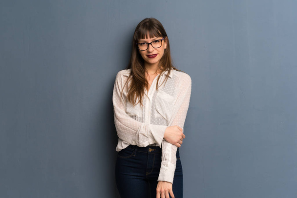 Γυναίκα με τα γυαλιά πάνω από μπλε τοίχο χαμογελά - Φωτογραφία, εικόνα