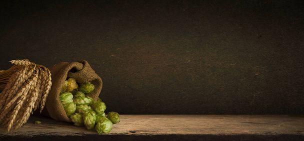 Hop twigs frame over wooden cracked table background. Vintage toned. Beer ingredients. Beautiful fresh-picked whole hops with green leaves border design close-up. Brewing concept, Vertical image - Фото, зображення