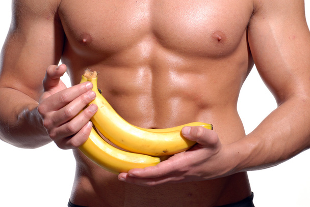 Shaped and healthy body man holding a fresh bananas - 写真・画像
