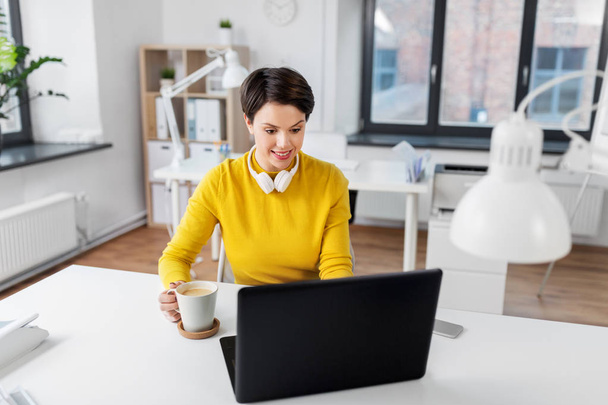 businesswoman with laptop drinks coffee at office - Zdjęcie, obraz