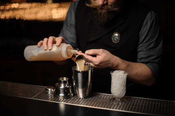 Bartender pouring a delicious alcoholic drink from the steel jigger and essence - Foto, imagen