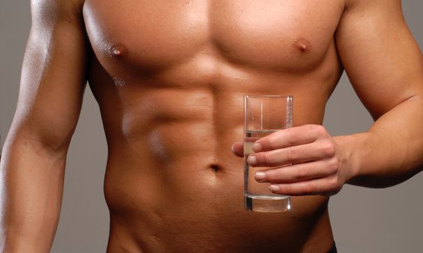Shaped and healthy man holding a mineral water glass - Foto, imagen