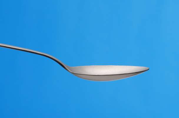 Sugar teaspoon on blue background. - Фото, изображение
