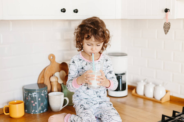 Little girl wearing pajamas drinking milk - Foto, Imagem