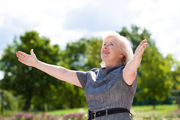 Happy elderly woman on the background of summer park - Фото, изображение