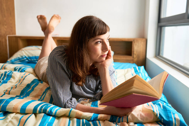Красива жінка читає у своїй спальні з хорошою книгою
 - Фото, зображення