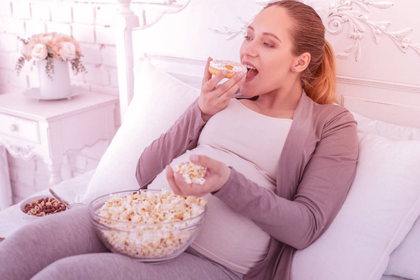 Fair-haired good-looking pregnant woman in comfortable clothes having a snack - Foto, immagini