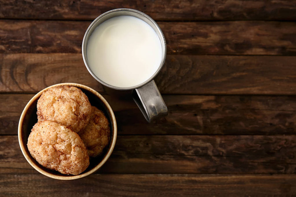 Bol avec des biscuits savoureux et une tasse de lait sur une table en bois
 - Photo, image