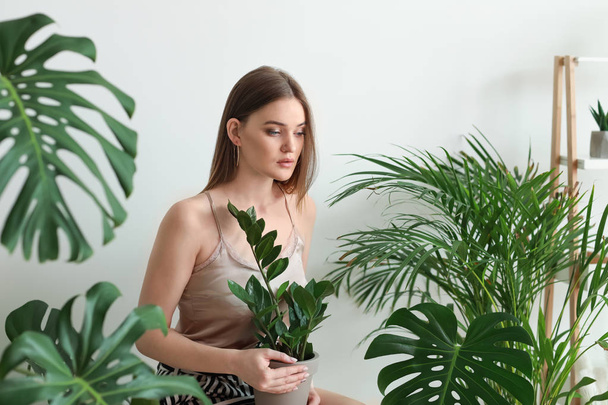 Portrait of beautiful woman with green tropical plants on light background - Fotografie, Obrázek