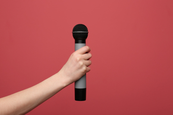Female hand with microphone on color background - Fotó, kép