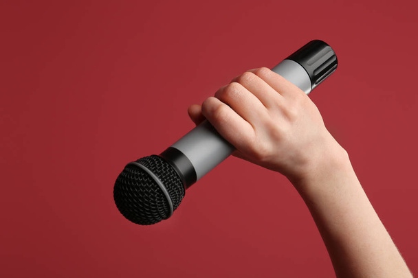 Female hand with microphone on color background - Foto, Imagem