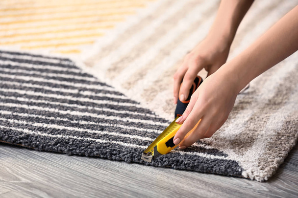 Vrouw met tape te meten snijden tapijt op de vloer - Foto, afbeelding