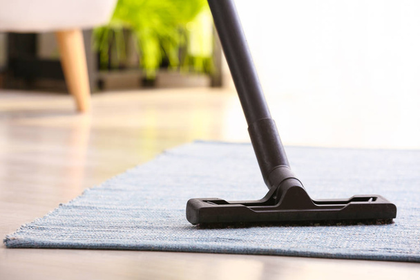 Cepillo de aspiradora en la alfombra en la habitación
 - Foto, imagen
