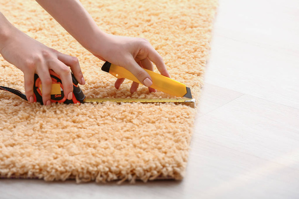 Woman cutting carpet at home - Foto, Bild