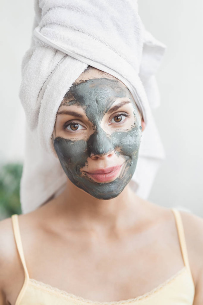 Face Skin care. Attractive Young Woman Wrapped in Bath Towel, applying clay mud mask to face. Skin care concept. Girl taking care of complexion. Beauty treatments - Valokuva, kuva