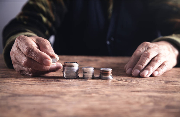 Elderly woman counting money on wooden table. - 写真・画像