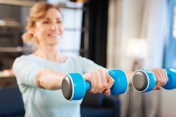 Sportive mature lady having exercises with dumbbells - Фото, зображення