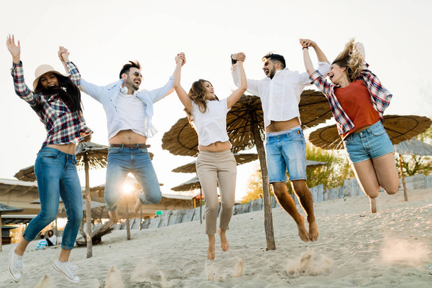 Amici felici che saltano e si divertono sulla spiaggia in estate
 - Foto, immagini