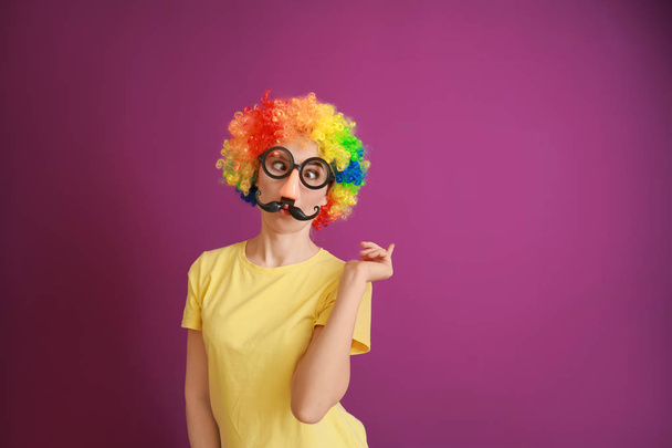 Весела жінка з партією декор на день сміху на кольоровому фоні - Фото, зображення