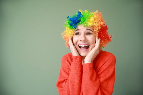 Grappige vrouw met pruik voor april Fools ' dag viering op kleur achtergrond - Foto, afbeelding