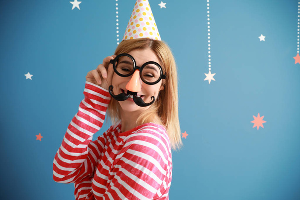 Funny woman with party decor for April Fools' Day on color background - Foto, Imagem