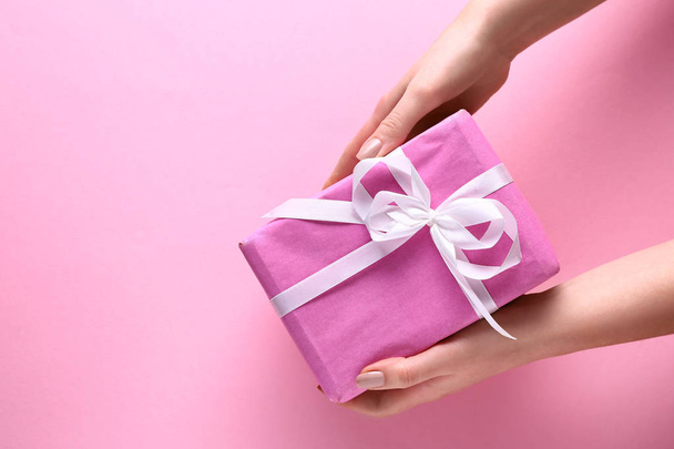 Manos femeninas con caja de regalo sobre fondo de color - Foto, Imagen