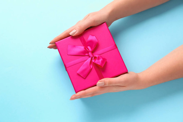 Female hands with gift box on color background - Fotografie, Obrázek