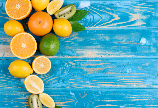 Vista desde arriba de las frutas sobre un tablero de madera y fondo azul
 - Foto, Imagen