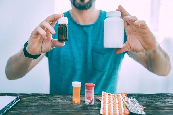 Ill man showing different types of pills and medicine - Foto, Imagen