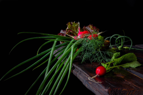 Fresh vegetables onion green feather radish on a dark wooden background in rustic style with copy space - Fotografie, Obrázek