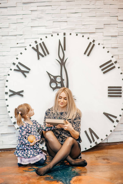 mother and daughter reading book on vintage clock background  - Photo, image