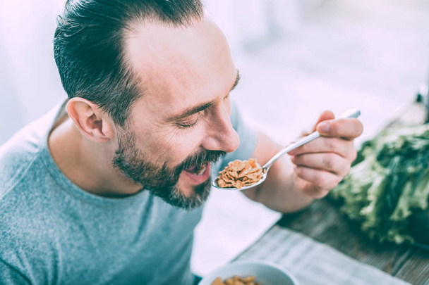 Hungry attractive man eating cereals for breakfast - Foto, Imagem