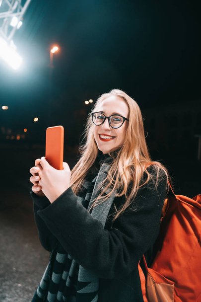Blonde woman with smartphone at night in the street. - Fotoğraf, Görsel