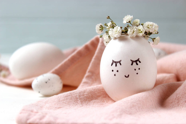 composition for Easter with a place to insert text. cute egg in a flower wreath and painted face. - Fotografie, Obrázek