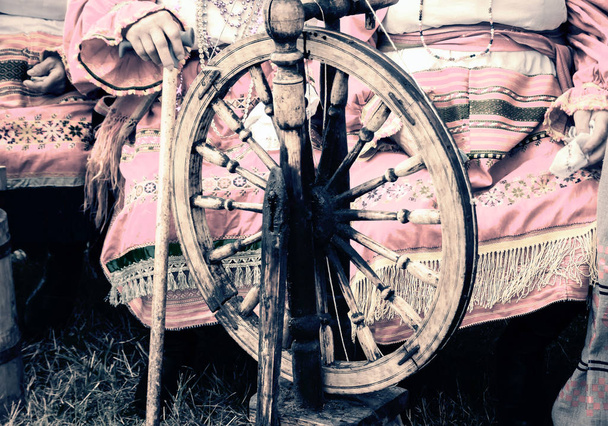 Старые деревянные крутящиеся колеса и женщина в национальной одежде. - Фото, изображение