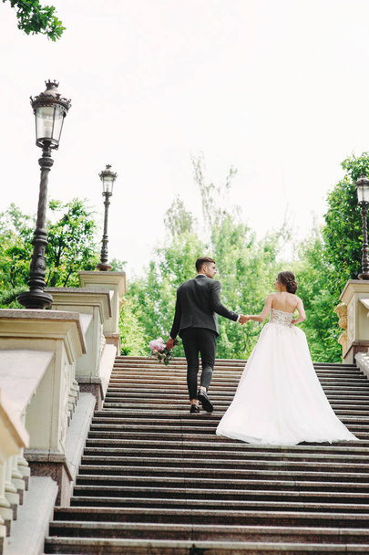 panna młoda i pan młody spacerujący po schodach w parku - Zdjęcie, obraz