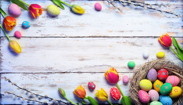 Пасхальна листівка - розмальовані яйця в гнізді і тюльпани на вінтажному дошці
 - Фото, зображення