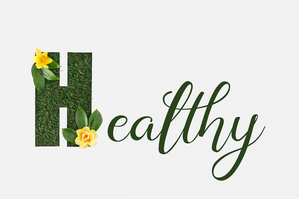 a levelek és a sárga nárcisz elszigetelt fehér zöld egészséges betűkkel felülnézet - Fotó, kép