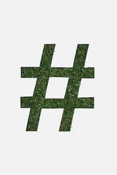 top view of cut out hashtag sign on green grass background isolated on white - Foto, afbeelding