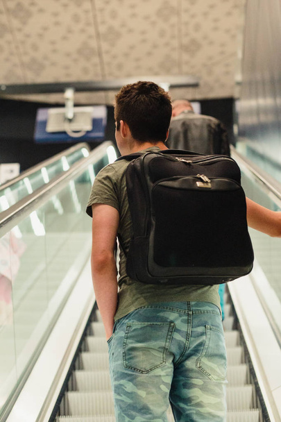 Young man standing on a escalator in the railway station - Photo, Image
