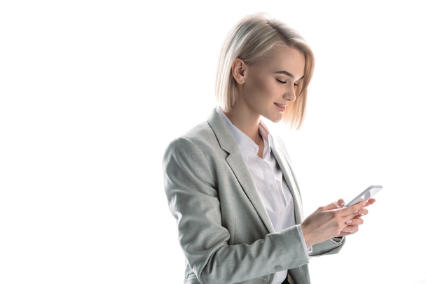 attractive, smiling blonde businesswoman using smartphone isolated on white - Φωτογραφία, εικόνα
