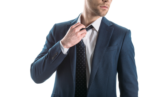 partial view of businessman in suite touching tie isolated on white - Valokuva, kuva