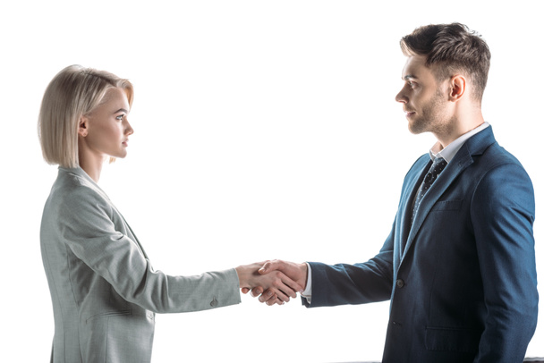 young business partners shaking hands and looking at each other isolated on white - Foto, afbeelding